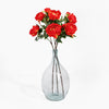 Clear glass vase with red flowers on a white background