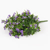 An artificial flower bouquet featuring small purple blossoms and green leaves on a solid white background.