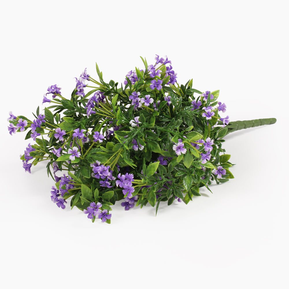An artificial flower bouquet featuring small purple blossoms and green leaves on a solid white background.