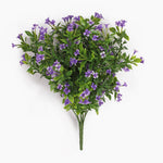An artificial flowering plant bouquet with dense green foliage and small purple blossoms, photographed against a plain white background.