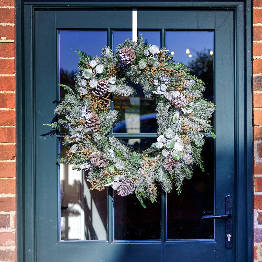 Decorative wreath on a blue door with brick walls.
