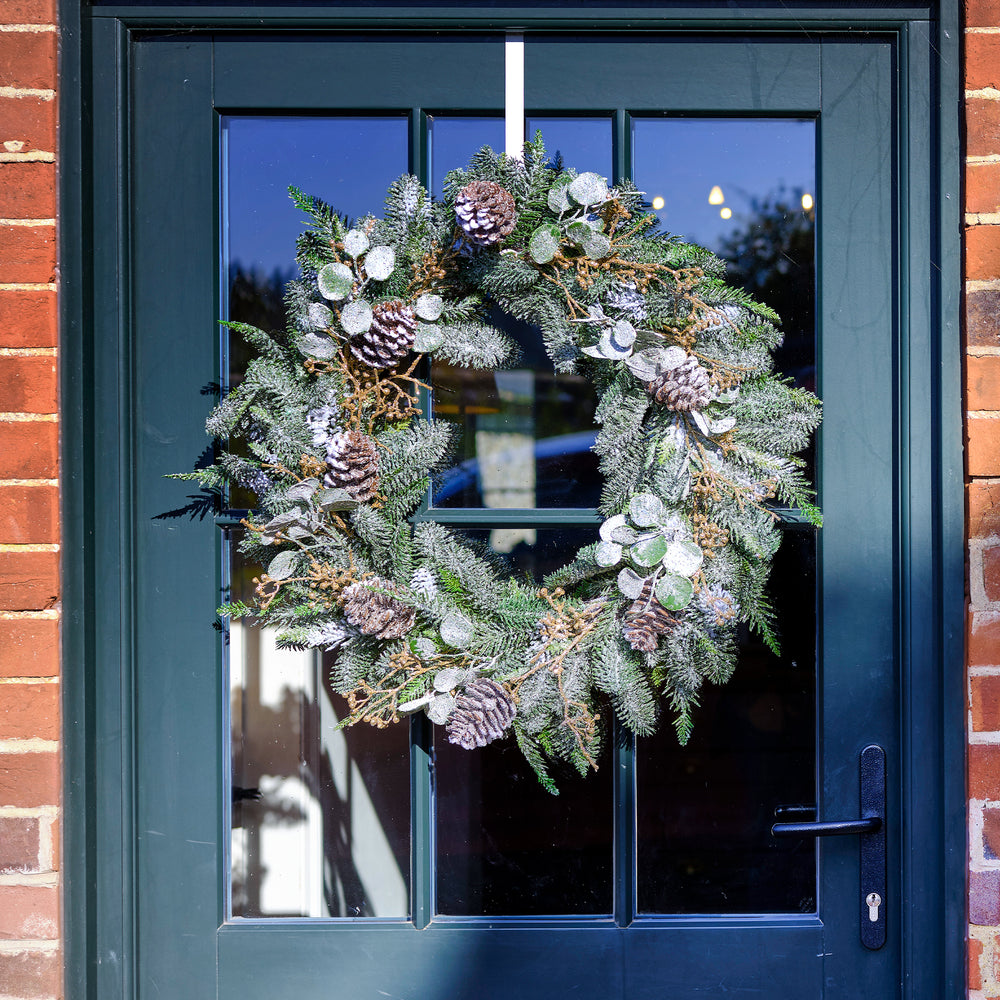 Decorative wreath on a blue door with brick walls.