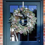 Decorative wreath on a blue door with brick walls.