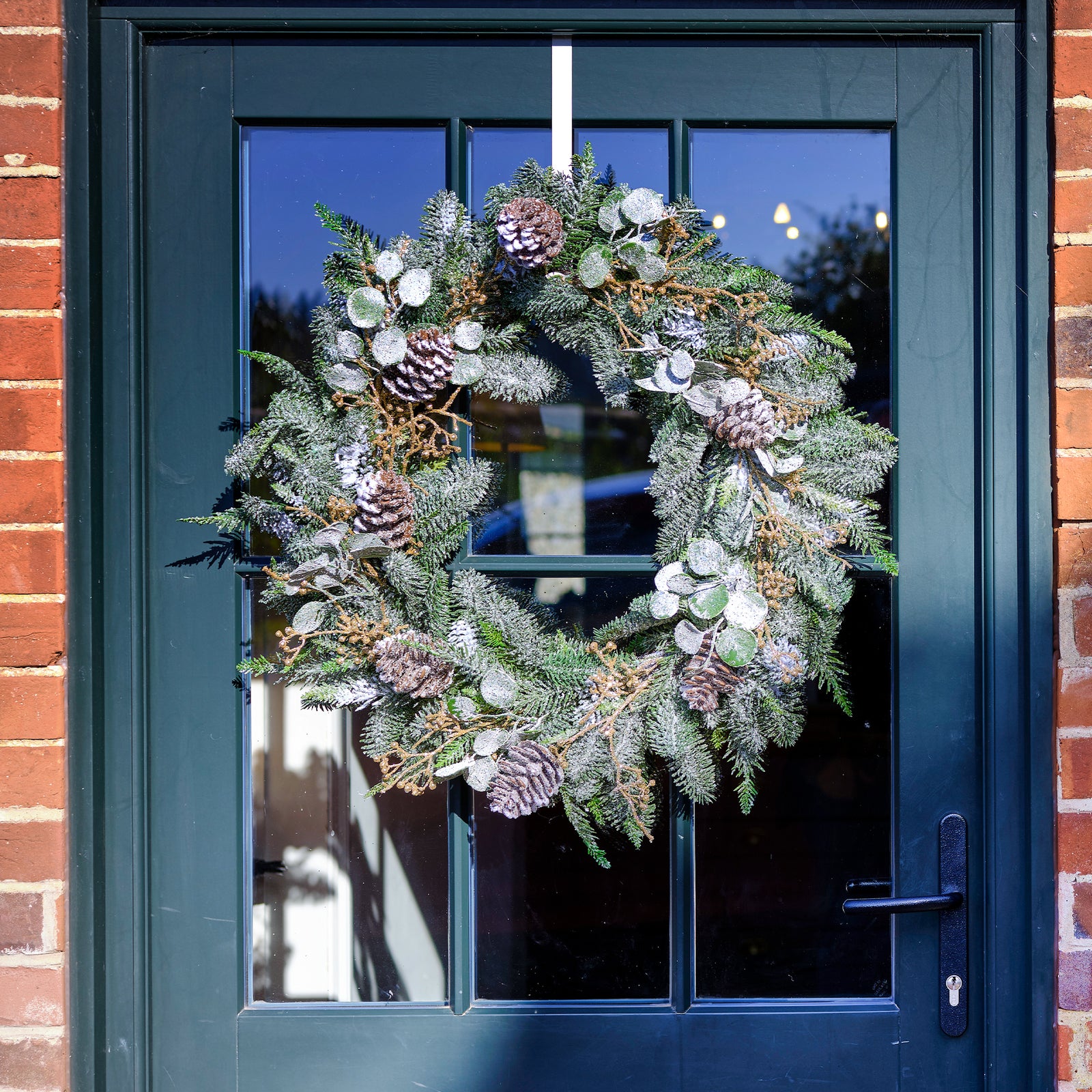 Decorative wreath on a blue door with brick walls.