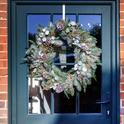 Decorative wreath on a blue door with brick walls.