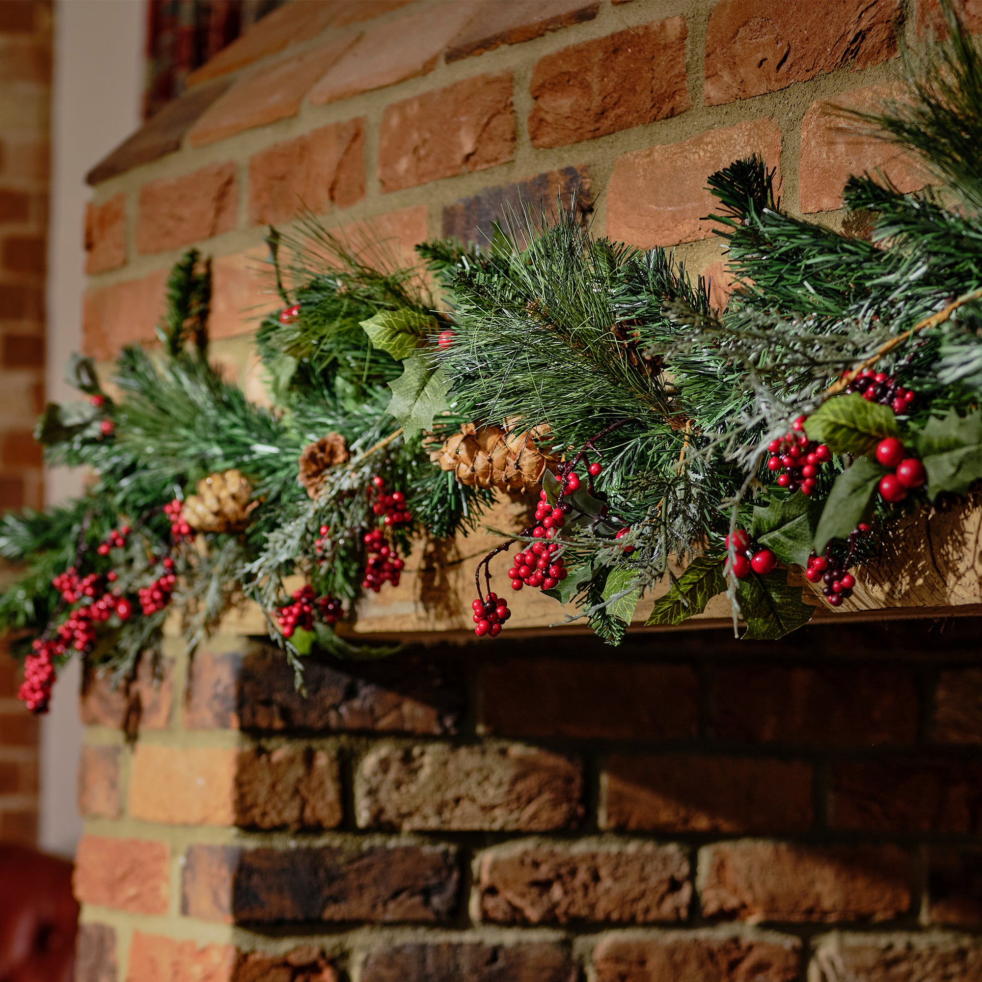 Decorative Christmas garland with greenery and berries on a brick fireplace.